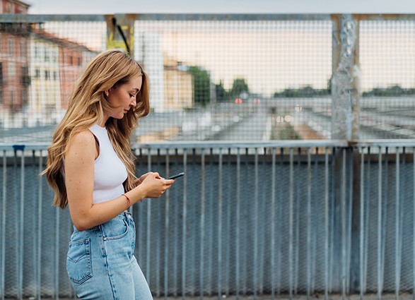 Young caucasian woman walking outdoor using smartphone texting m