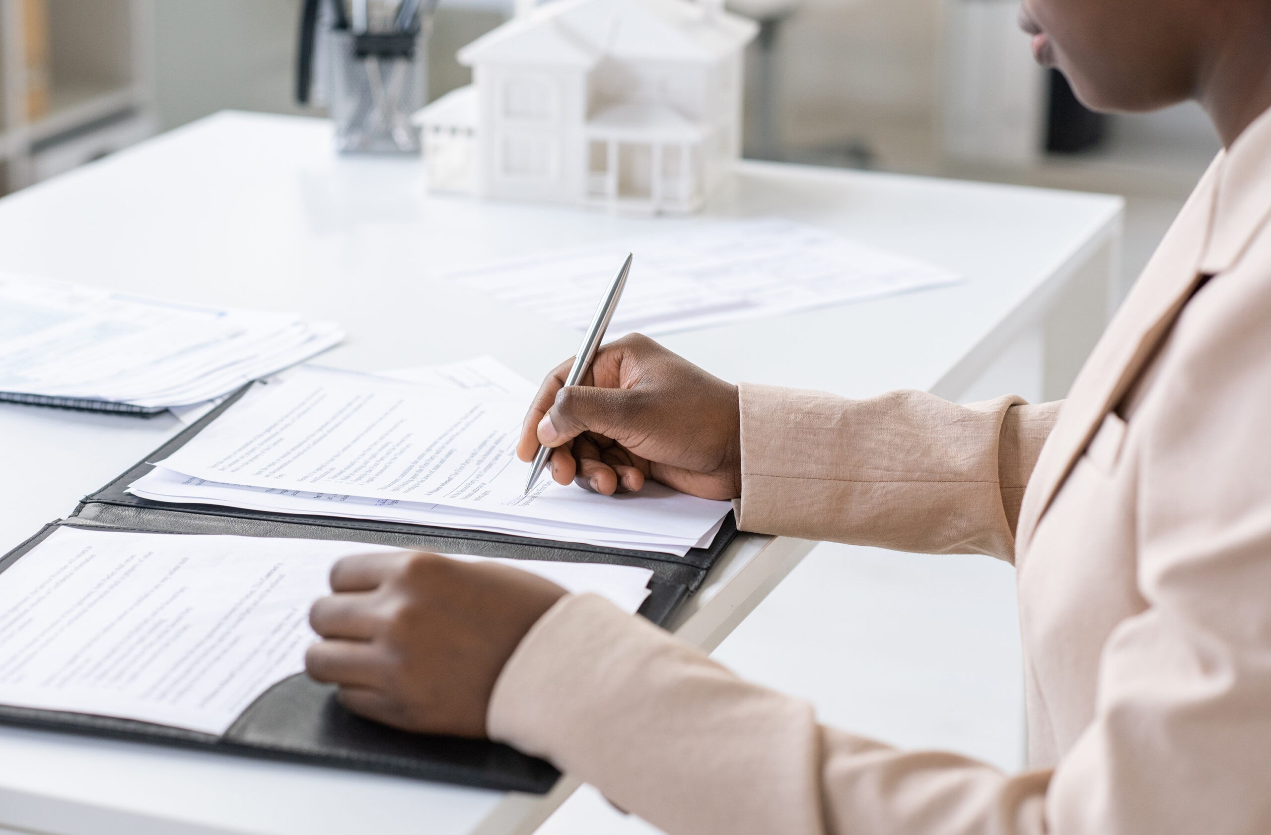 Hands of young African woman signing mortgage contract